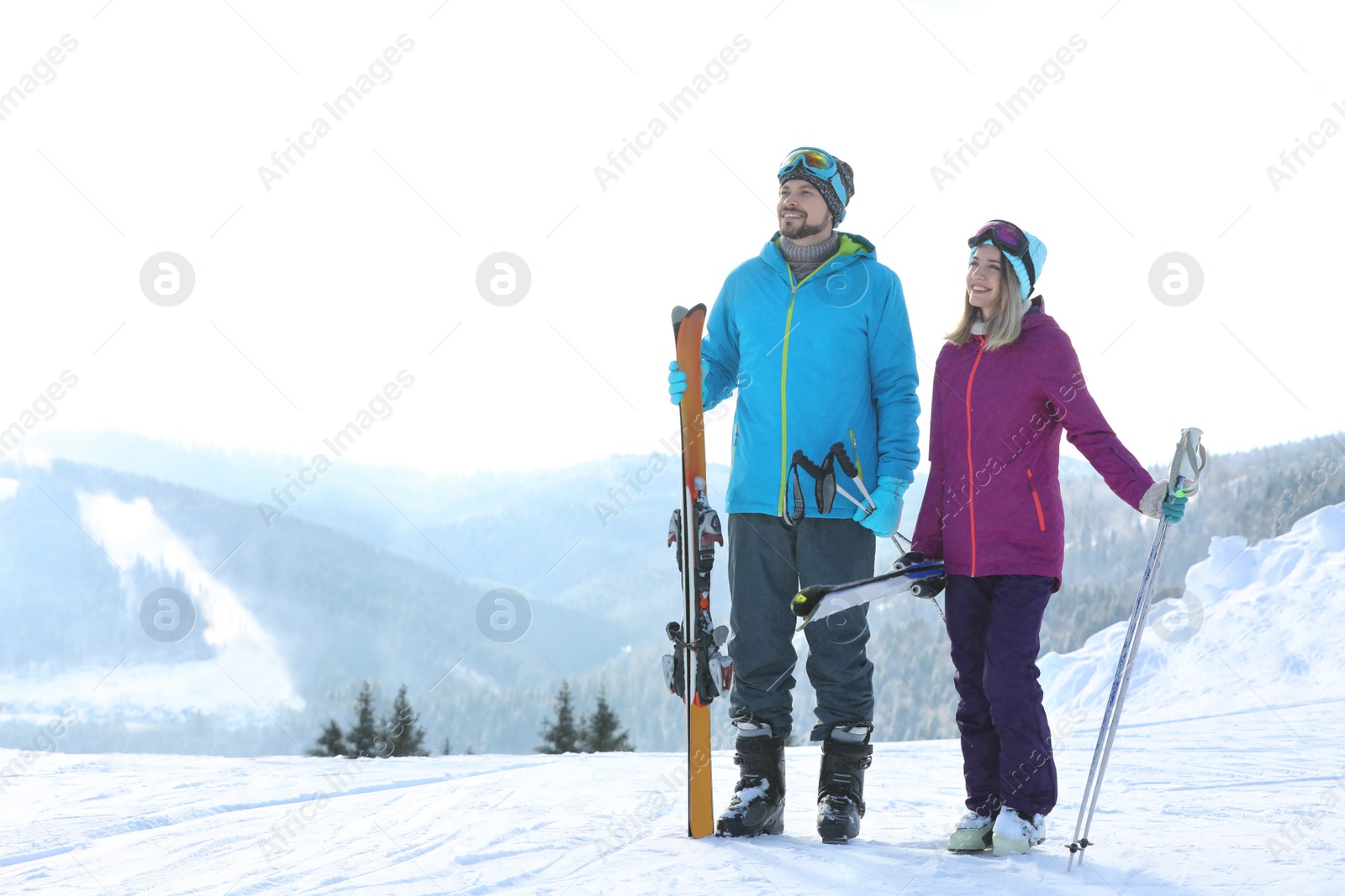 Photo of Happy couple with ski equipment spending winter vacation in mountains. Space for text