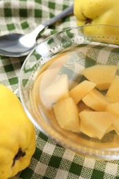 Photo of Delicious quince drink in glass bowl, fresh fruits and spoon on table, closeup