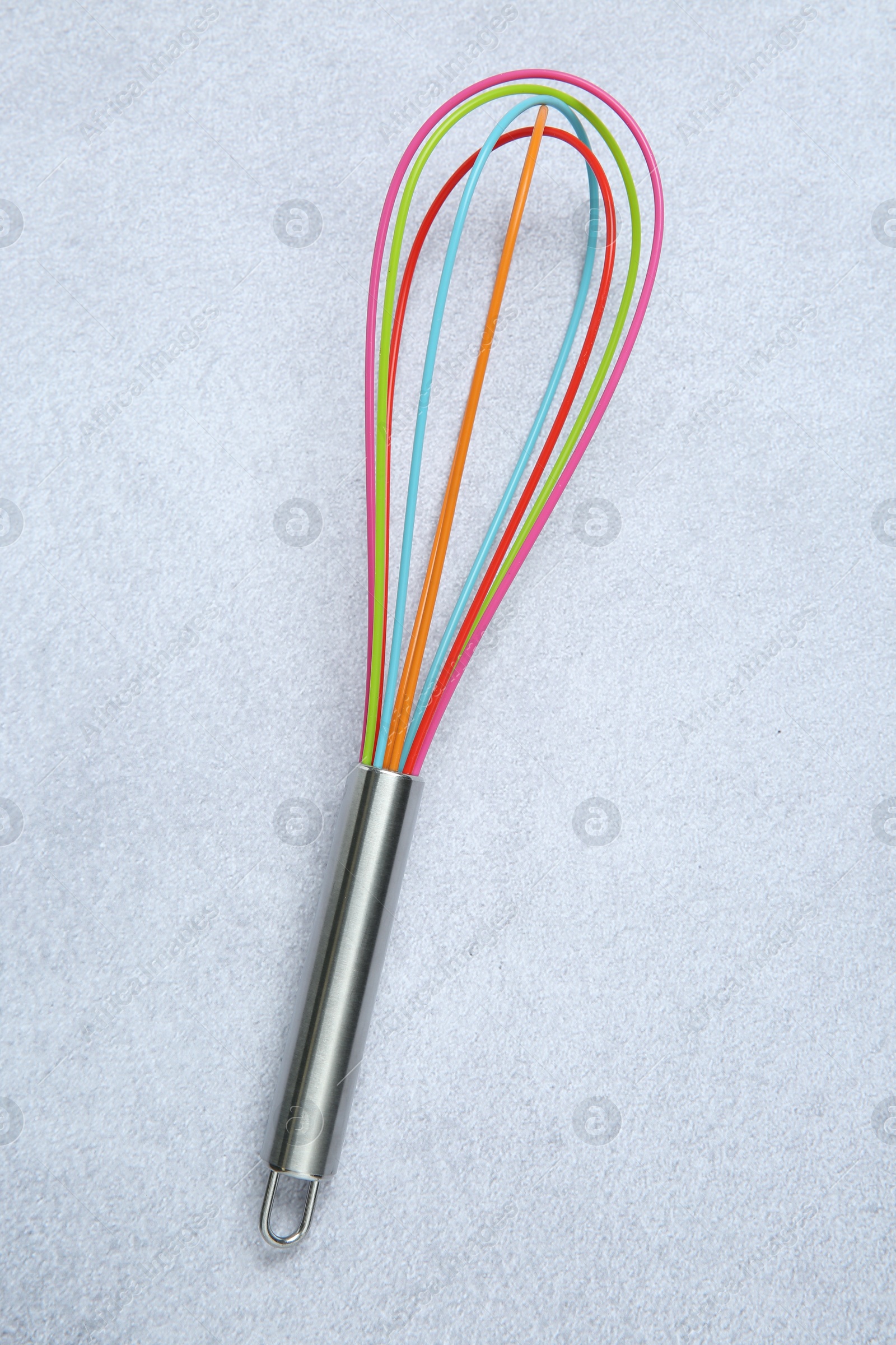 Photo of Bright whisk on gray table, top view. Kitchen tool