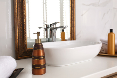 Stylish dispenser near mirror on white countertop