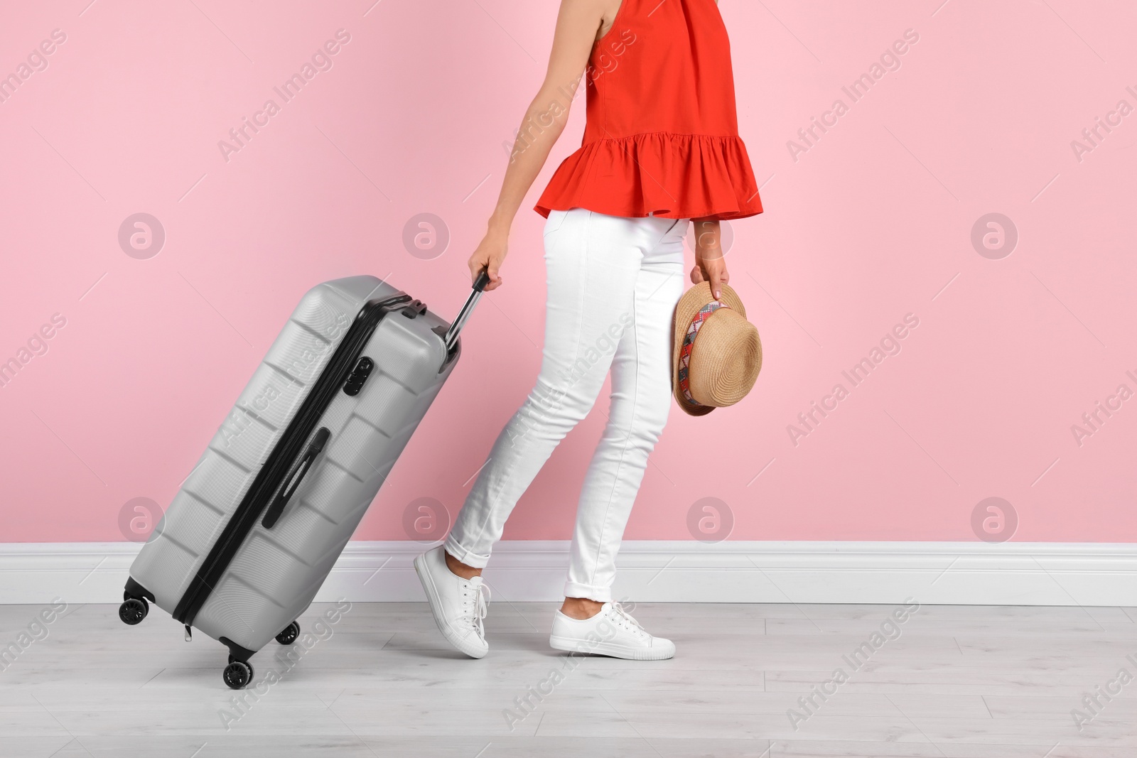 Photo of Woman with suitcase near color wall. Vacation travel