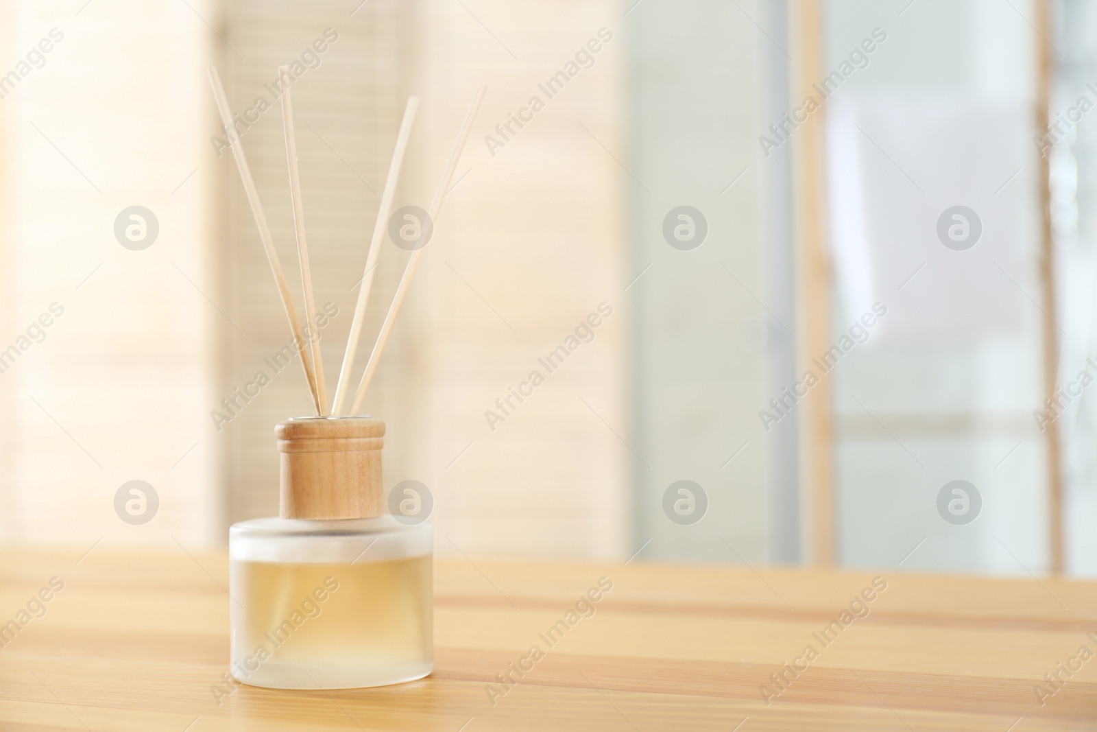 Photo of Reed air freshener on wooden table indoors. Space for text