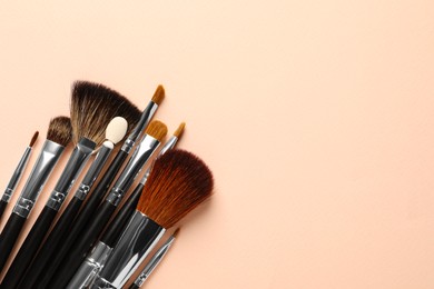 Photo of Different makeup brushes on light beige background, flat lay . Space for text