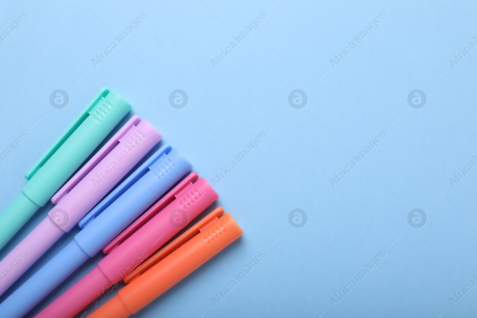 Photo of Many colorful markers on light blue background, flat lay. Space for text