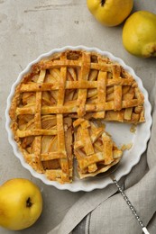 Tasty homemade quince pie with cake server and fresh fruits on light grey table, flat lay