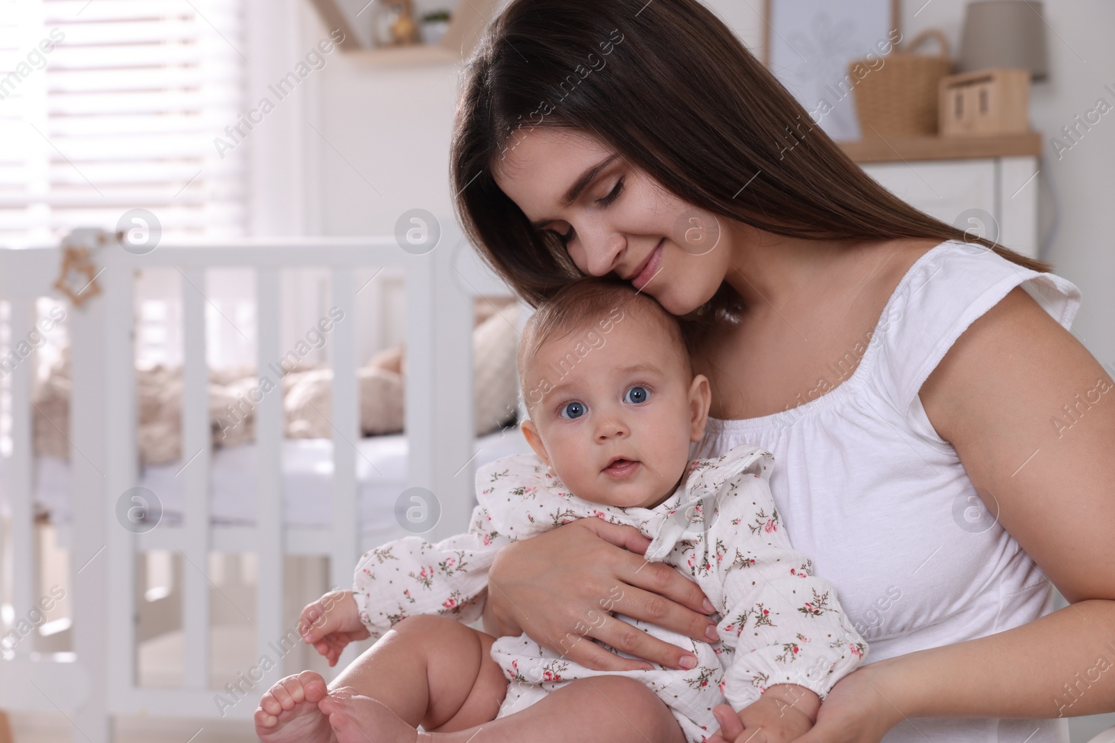 Photo of Happy young mother with her baby daughter in nursery