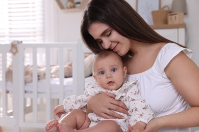 Photo of Happy young mother with her baby daughter in nursery