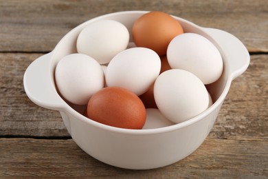 Photo of Unpeeled boiled eggs in saucepan on old wooden table, closeup