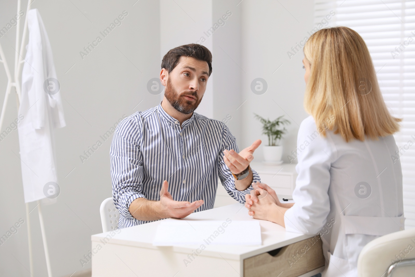 Photo of Doctor consulting patient at white table in clinic