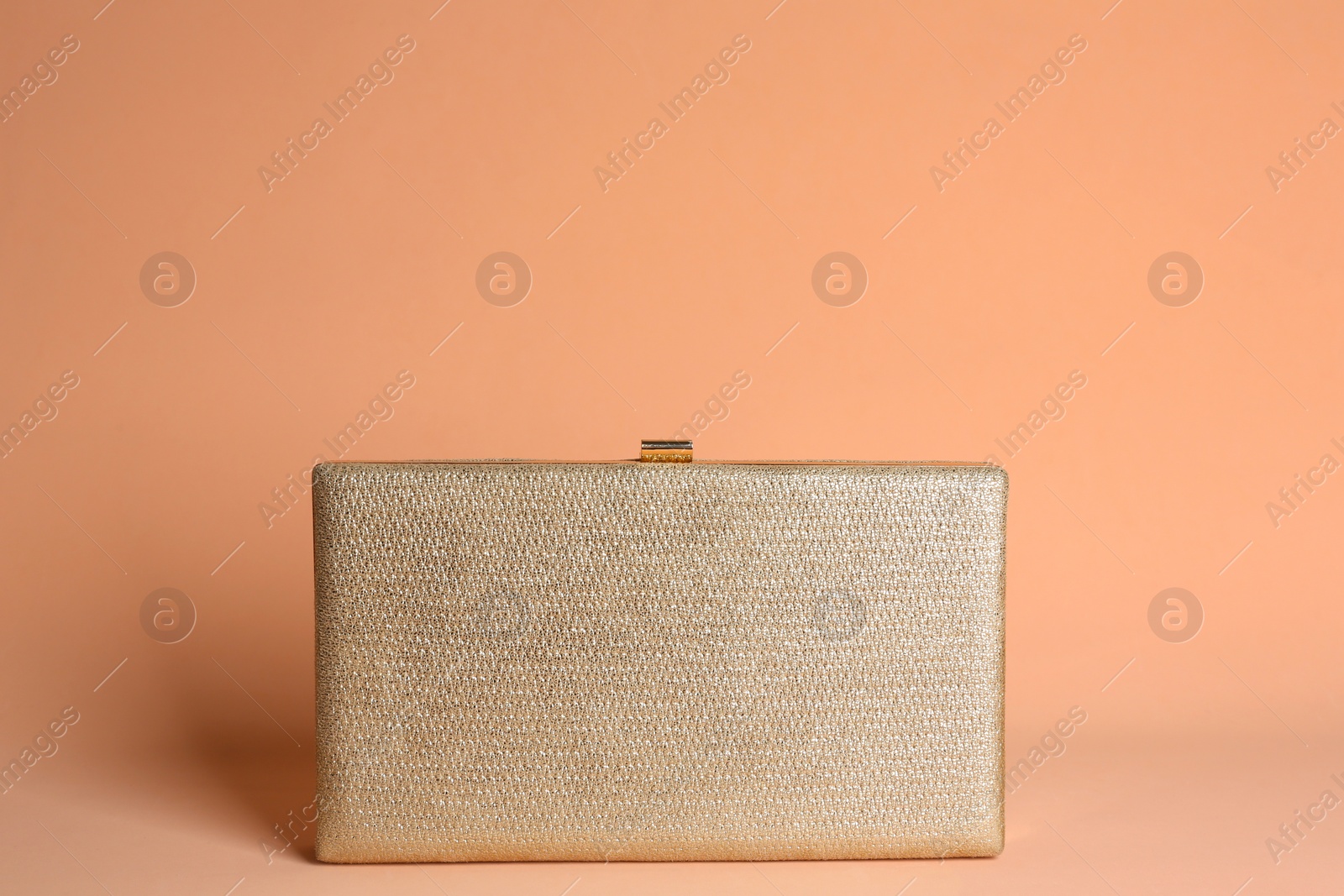 Photo of Golden stylish woman's bag on pale pink background