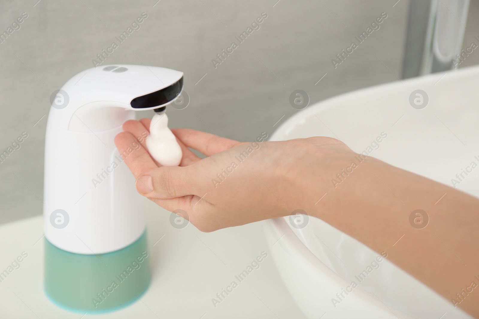 Photo of Woman using automatic soap dispenser in bathroom, closeup