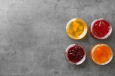 Photo of Jars with different sweet jam on grey background