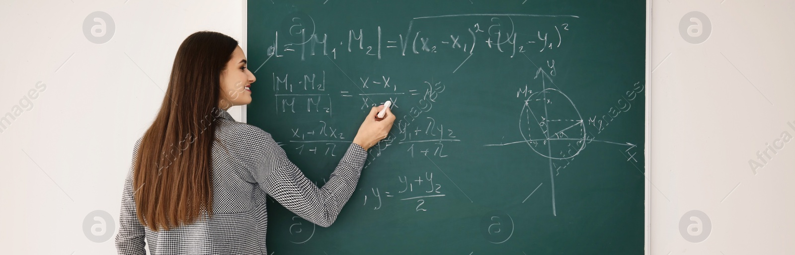 Image of Young teacher writing on chalkboard in classroom. Banner design