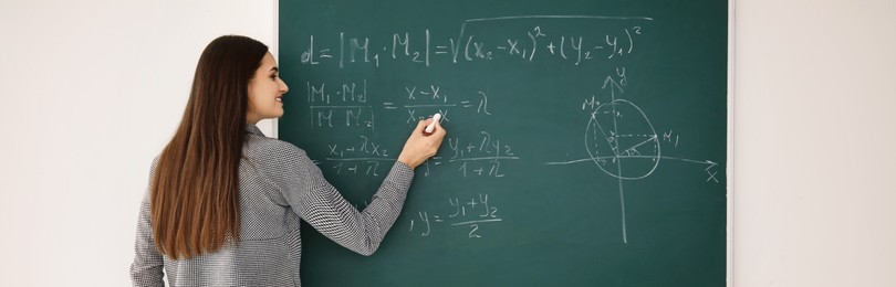 Image of Young teacher writing on chalkboard in classroom. Banner design