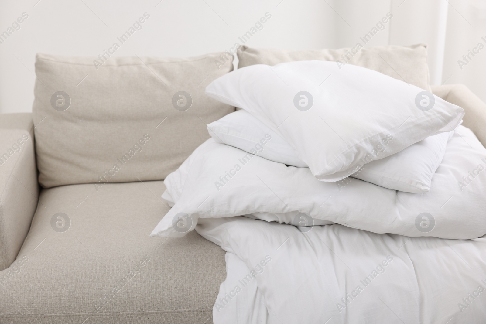 Photo of Soft pillows and duvet on sofa indoors