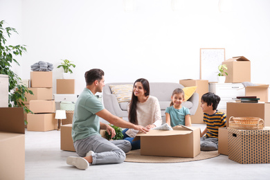 Happy family unpacking moving boxes at their new home