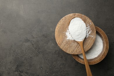 Baking powder in bowl and spoon on grey textured table, top view. Space for text