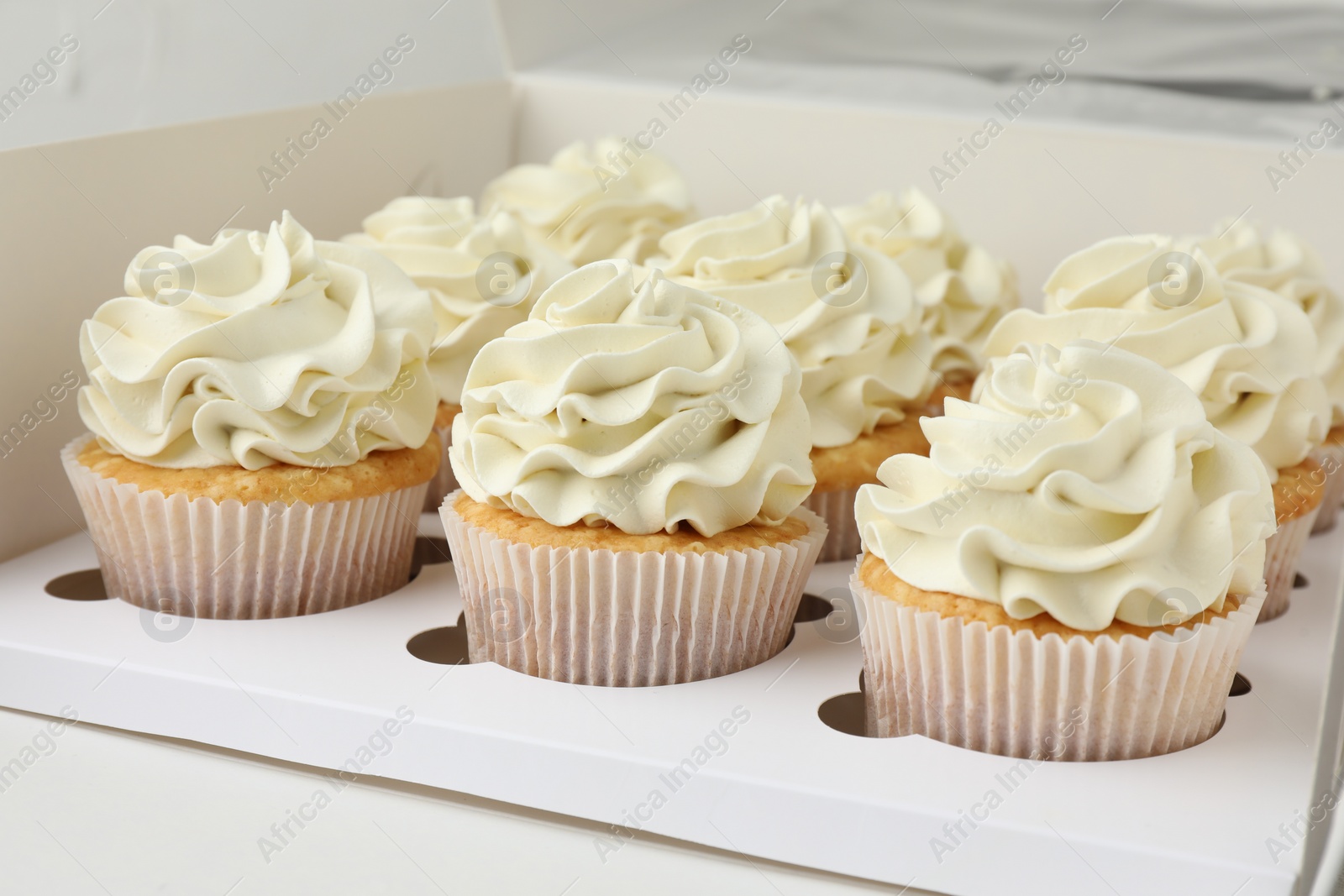 Photo of Tasty cupcakes with vanilla cream in box, closeup