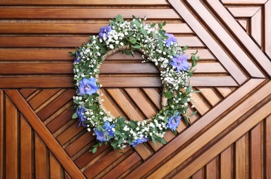 Beautiful flower wreath on wooden background, top view