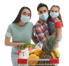 Family in medical masks with shopping cart full of groceries on white background