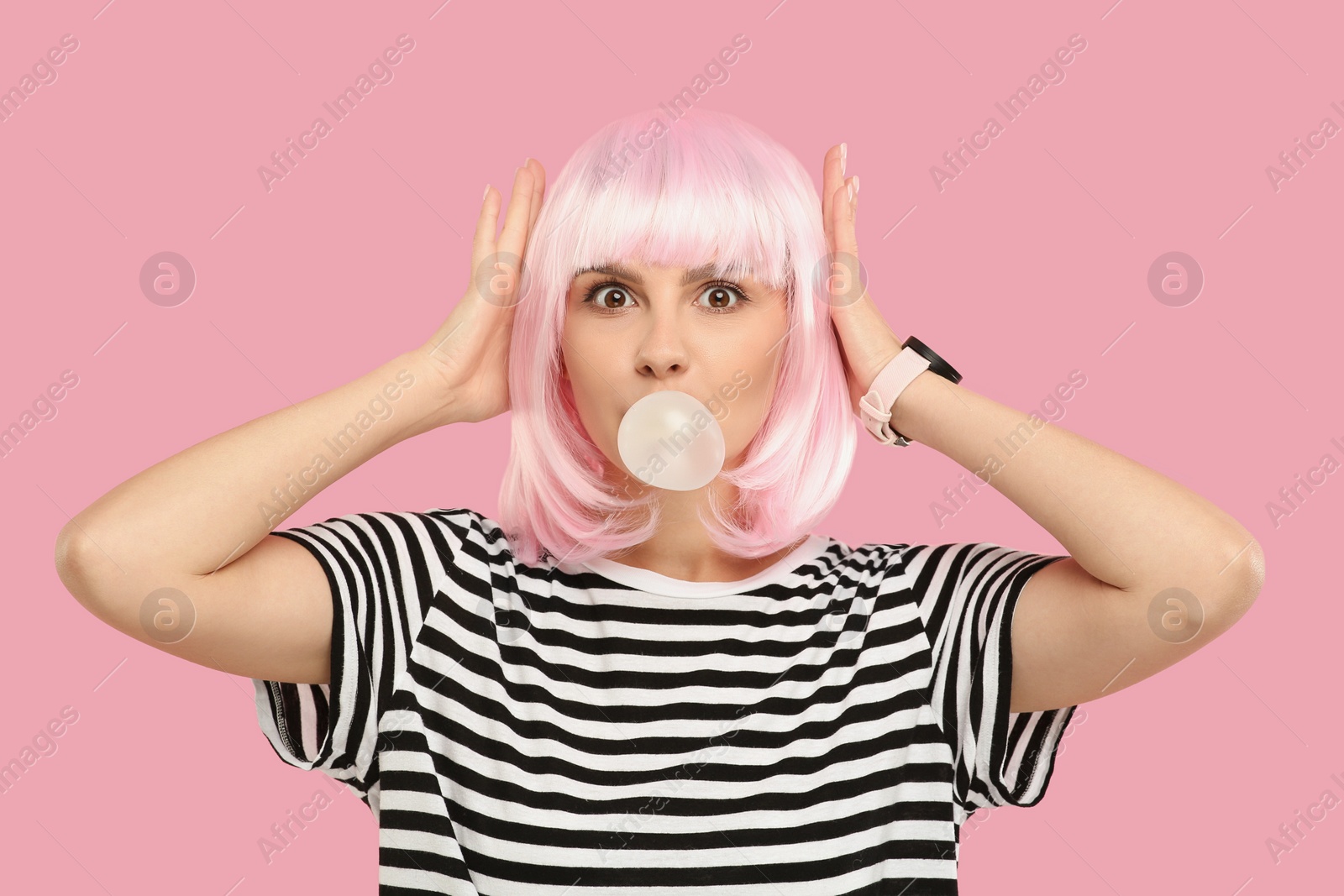 Photo of Beautiful woman blowing bubble gum on pink background