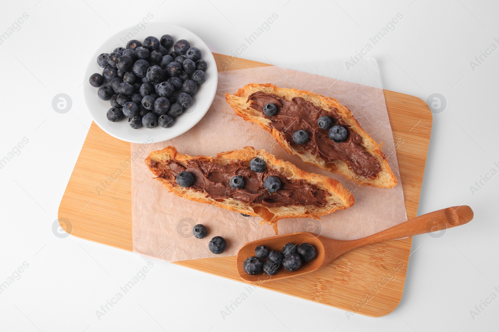 Photo of Tasty croissant with chocolate paste and blueberries on white background, above view