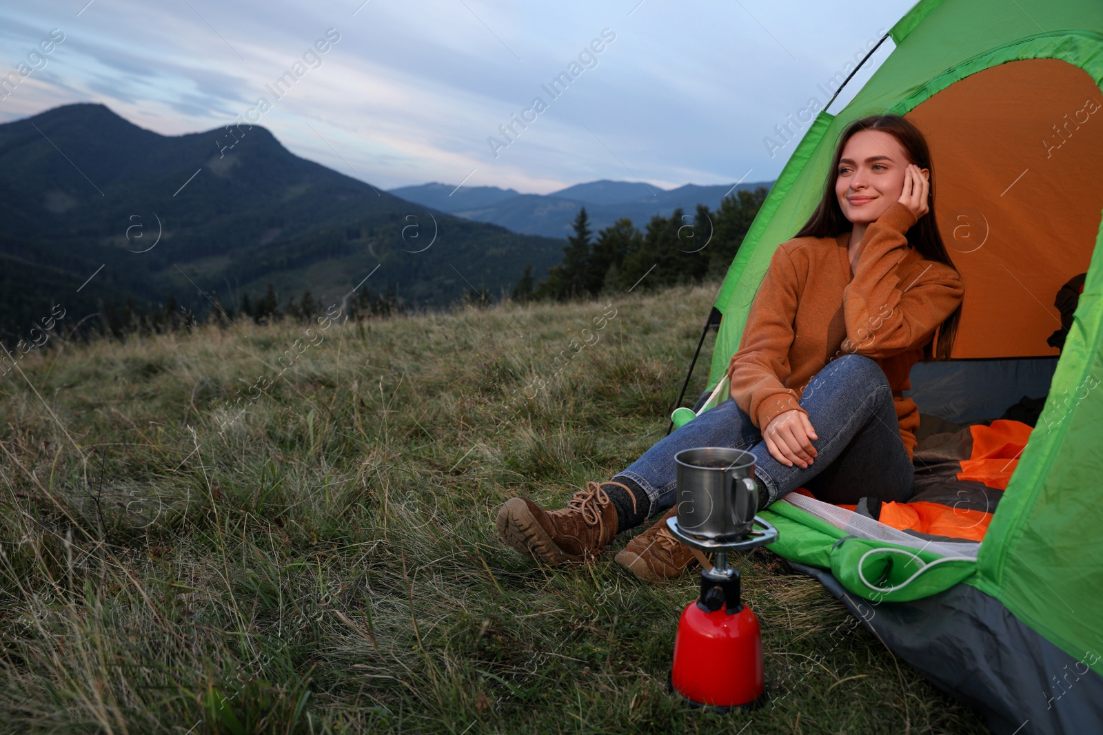 Photo of Young woman enjoying mountain landscape in camping tent