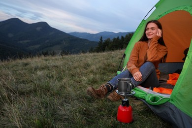 Young woman enjoying mountain landscape in camping tent
