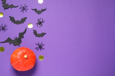 Flat lay composition with pumpkin, paper bats and spiders on purple background, space for text. Halloween decor