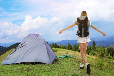 Image of Tourist with travel backpack near camp tent in mountains. Summer vacation trip