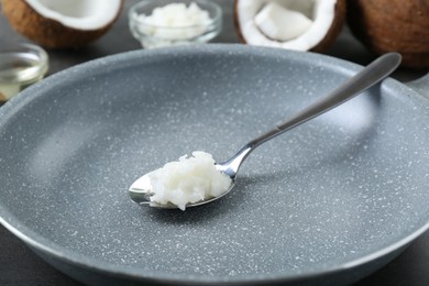 Photo of Frying pan with organic coconut cooking oil and spoon on table, closeup