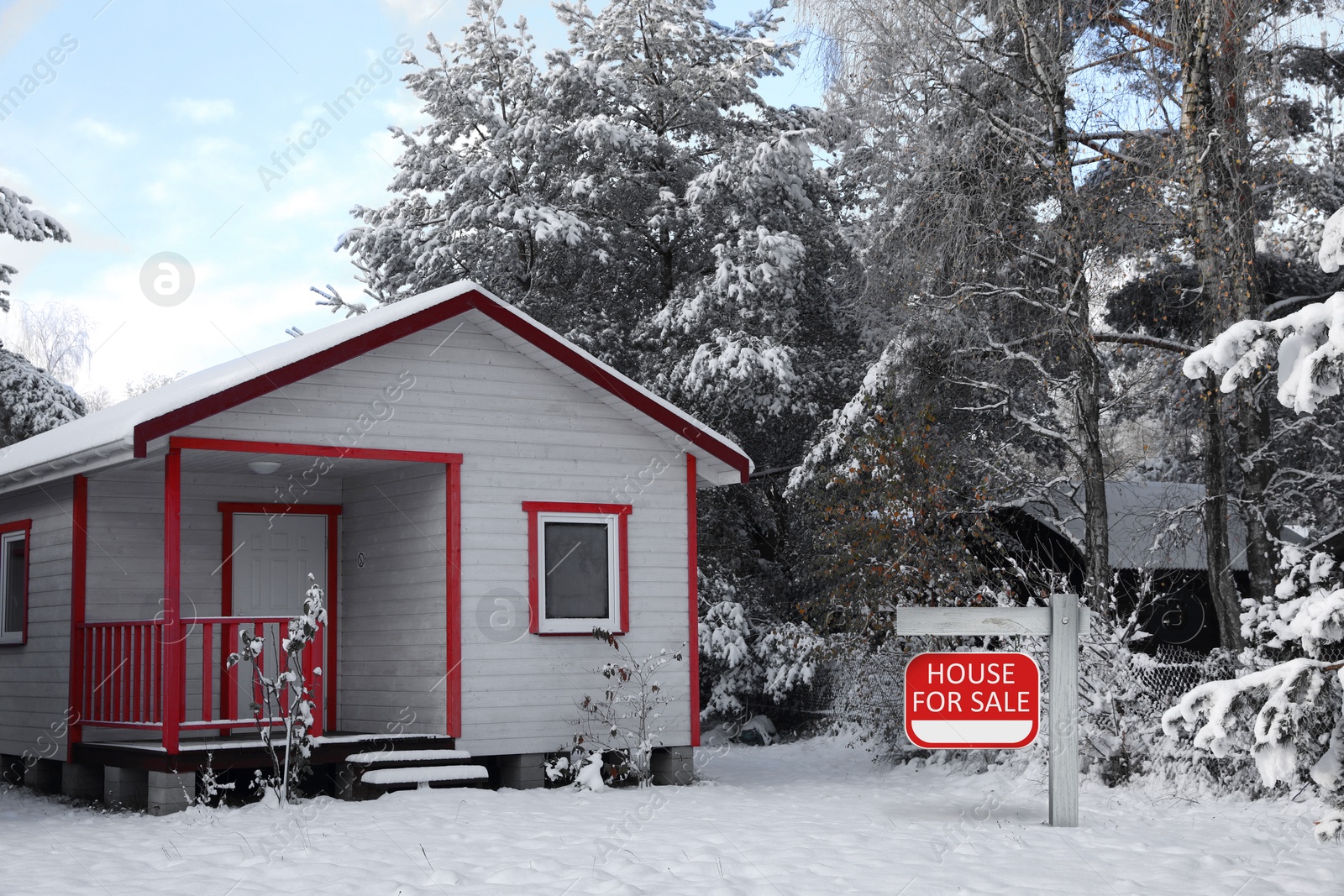 Image of Sale sign near beautiful house outdoors in winter. Red signboard with words