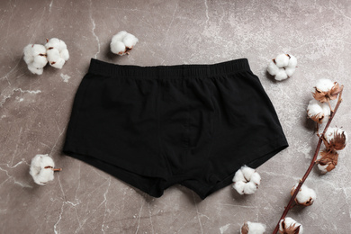 Photo of Men's underwear and cotton flowers on brown marble background, flat lay