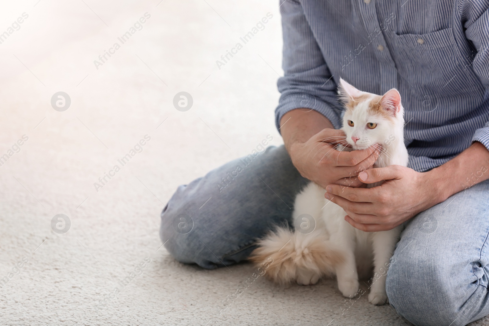 Photo of Young man with cute cat sitting on floor at home