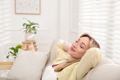 Beautiful young woman relaxing on sofa at home, space for text