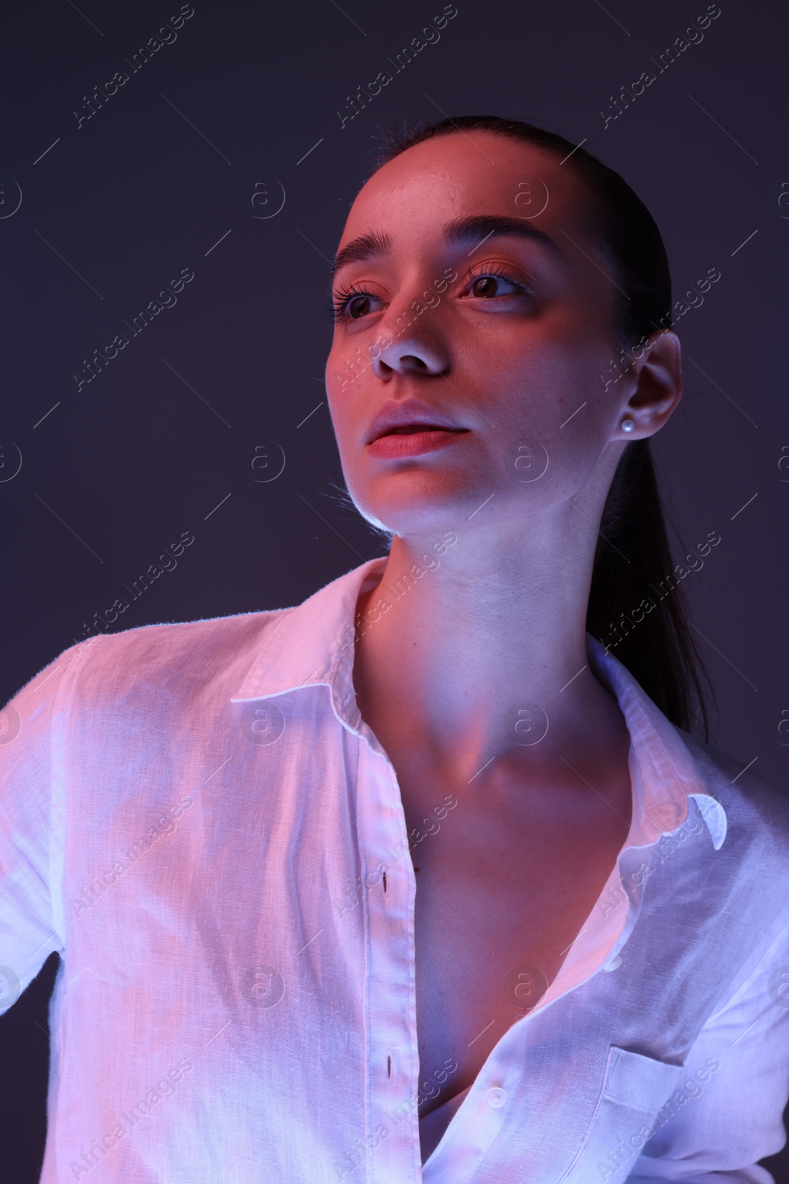 Photo of Portrait of beautiful young woman on dark purple background with neon lights