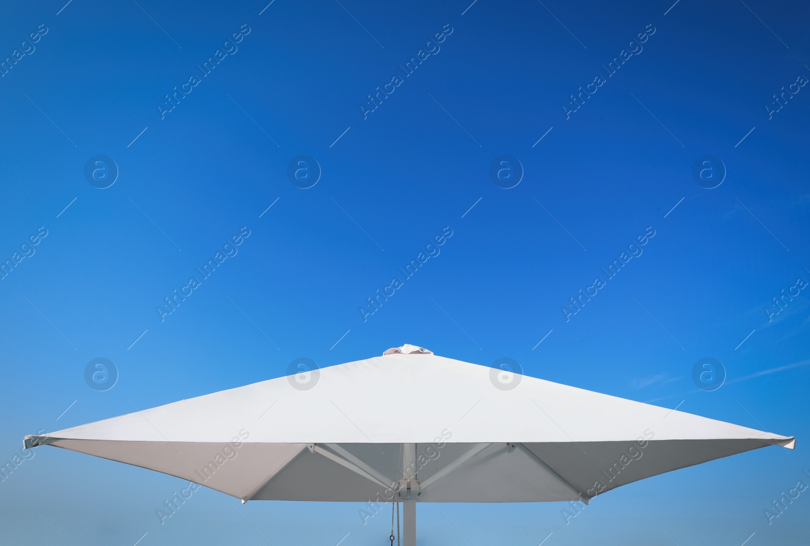 Photo of White beach umbrella against blue sky on sunny day
