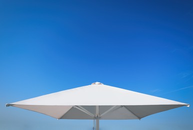 Photo of White beach umbrella against blue sky on sunny day