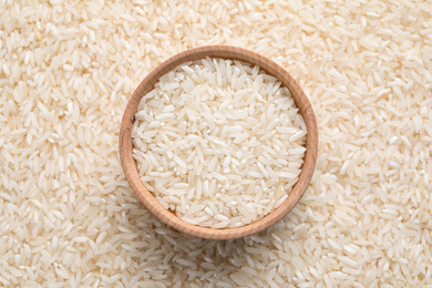 Photo of Pile of polished rice and wooden bowl, top view