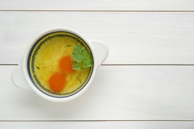 Photo of Delicious chicken bouillon with carrot and parsley on white wooden table, top view. Space for text