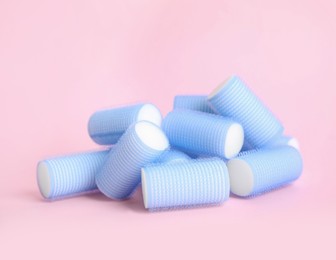 Photo of Many light blue hair curlers on pink background