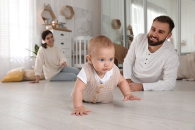 Happy parents watching their baby crawl on floor at home