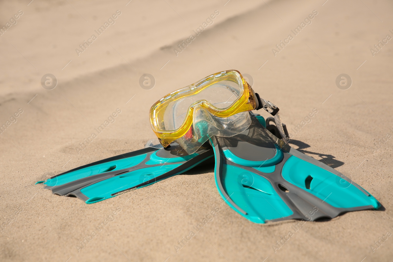 Photo of Pair of flippers and diving mask on sandy beach