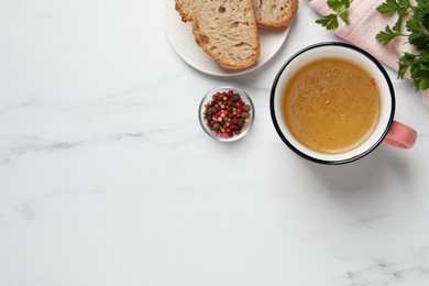 Photo of Hot delicious bouillon in cup on white marble table, flat lay. Space for text