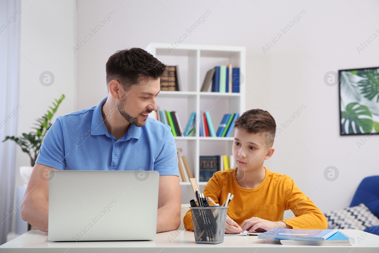 Photo of Dad helping his son with homework in room