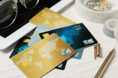 Photo of Different credit cards, tablet and stationery on white wooden table