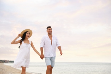 Photo of Lovely couple walking on beach. Space for text