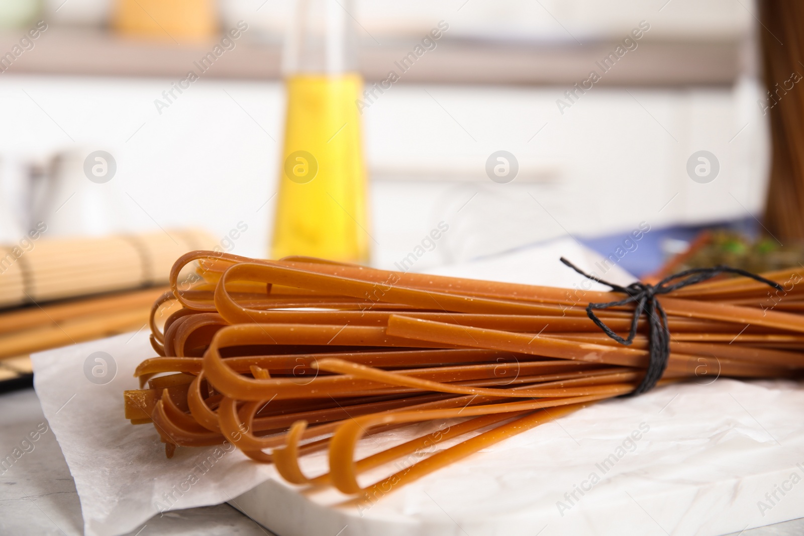 Photo of Tied uncooked buckwheat noodles on kitchen table, closeup