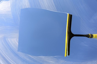 Photo of Squeegee and cleaning foam on glass, closeup