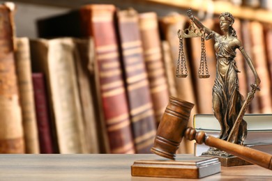 Image of Law. Statue of Lady Justice, gavel and books on wooden table indoors, space for text